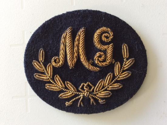 M.G ( Machine Gun) good bullion on dark blue wool trade badge